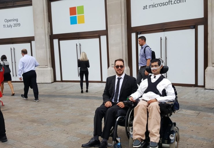 In front of the boarded-up Microsoft Store with a sign saying “Opening 11th July 2019” 